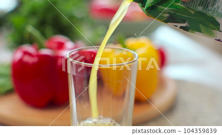 Person pouring fresh orange juice into a transparent glass in the modern kitchen. Organic vitamin drink. 104359839