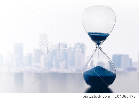 An image of time management in business. Blue hourglass and buildings background. An image of time management in business. Blue hourglass and buildings background. 104360475