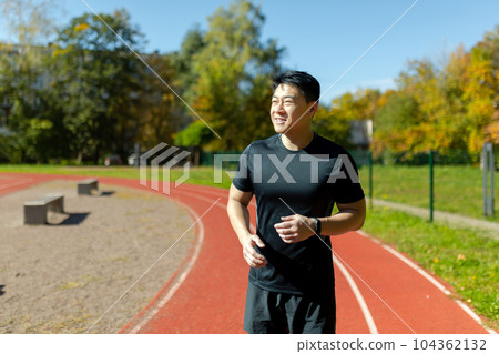 Young successful asian man jogging at daytime in stadium, man running and doing fitness active exercise in sports suit, active lifestyle. Young successful asian man jogging at daytime in stadium, man running and doing fitness active exercise in sports suit, active lifestyle. 104362132