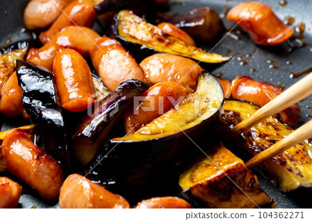 A cooking scene where eggplant and wiener sausage are fried in a frying pan. A cooking scene where eggplant and wiener sausage are fried in a frying pan. 104362271