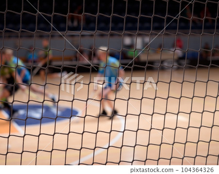 Floorball players in the indoor playground. A view through net 104364326