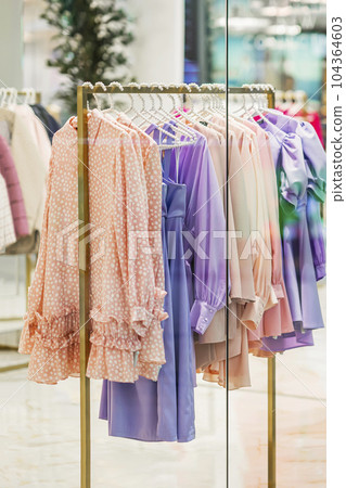 Youth clothes on hanger for sale in shop, assortment in clothing store. Blurred View through shop window Youth clothes on hanger for sale in shop, assortment in clothing store. Blurred View through shop window 104364603