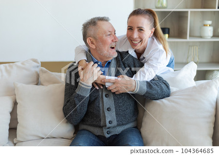 Happy family. Caring grown up daughter hugging loving older man father. Young woman embracing dad grandfather enjoying sweet bonding. Family generations together at home. Family moment love and care 104364685