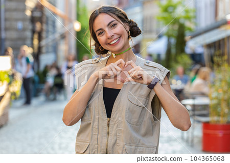 Young woman makes symbol of love, showing heart sign to camera, express romantic positive feelings 104365068