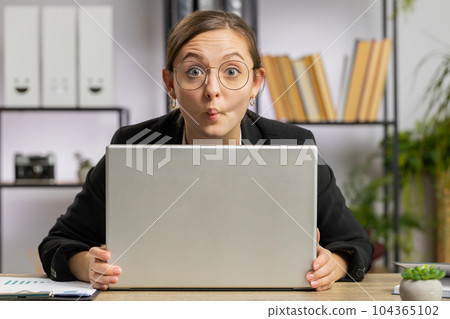 Office businesswoman hiding behind laptop computer making funny silly face fooling around disrespect 104365102