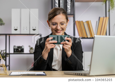 Business woman playing on smartphone exciting mobile application celebrate winning shooter game Business woman playing on smartphone exciting mobile application celebrate winning shooter game 104365203