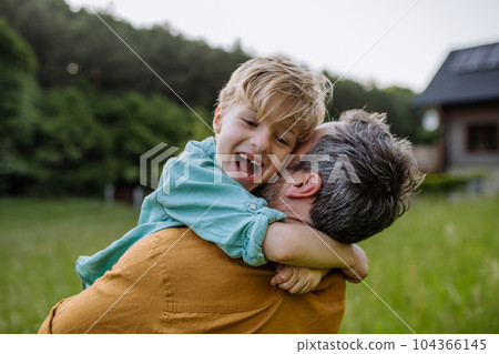 Rear view of father and his son looking at their house with solar panels on the roof. 104366145