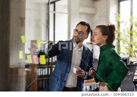 Young man showing notes in office to his colleague. 104366333
