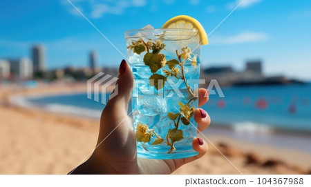 Blue refreshing cocktail at the beach in the woman hand on tropical beach background. 104367988