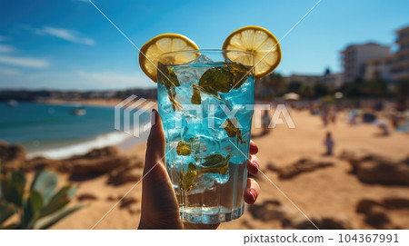 Blue refreshing cocktail at the beach in the woman hand on tropical beach background. Blue refreshing cocktail at the beach in the woman hand on tropical beach background. 104367991