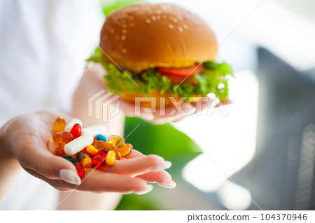 A woman is holding a handful of diet pills 104370946