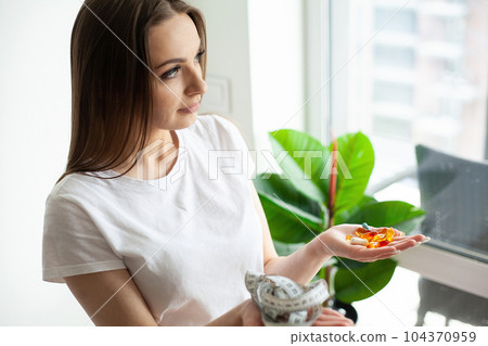 A woman is holding a handful of diet pills 104370959