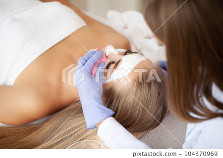 Young beautiful girl receiving facial mask in spa beauty salon Young beautiful girl receiving facial mask in spa beauty salon 104370969