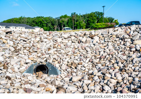 underground drainage storm drain with winged walls surrounded by rock for erosion control  104370991