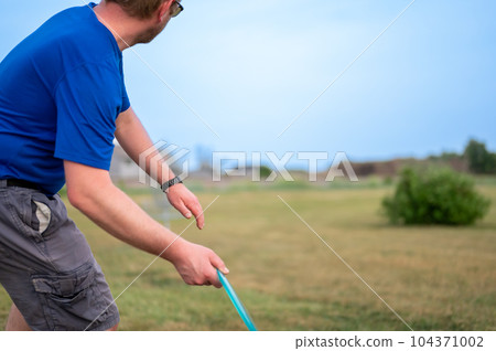 Selective focus on a Caucasian adult preparing to sidearm throw a disc golf towards the pin. Selective focus on a Caucasian adult preparing to sidearm throw a disc golf towards the pin. 104371002