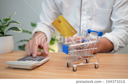 Man holding a credit card and pressing a calculator. Shopping concept. Cashless payment concept. 104371018