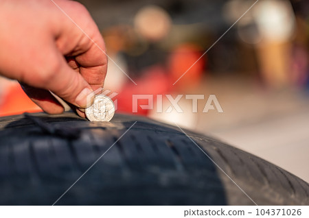 Quarter test on a tire to check wear by seeing the tread depth  104371026