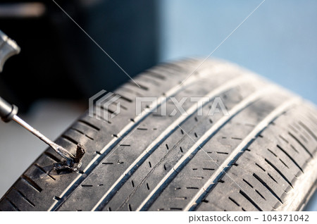 Repair plug being inserted to patch a nail tire puncture Repair plug being inserted to patch a nail tire puncture 104371042
