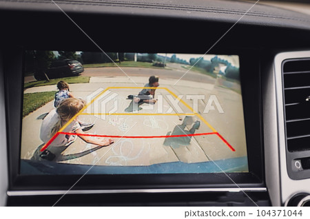 Children seen in a rear view backup camera drawing with chalk.  104371044