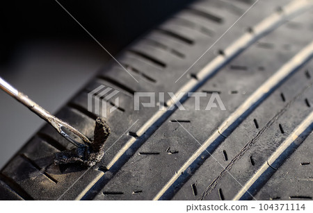Repair plug being inserted to patch a nail tire puncture Repair plug being inserted to patch a nail tire puncture 104371114