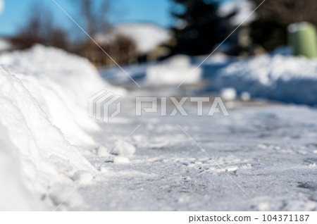 Selective focus ground level view of snow blown sidewalk section with path continuing.  104371187
