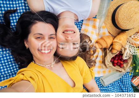 Selfie of two friends lying on blue blanket at picnic 104371652