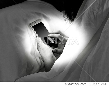 一個人在床上看智能手機的手_單色 104371781
