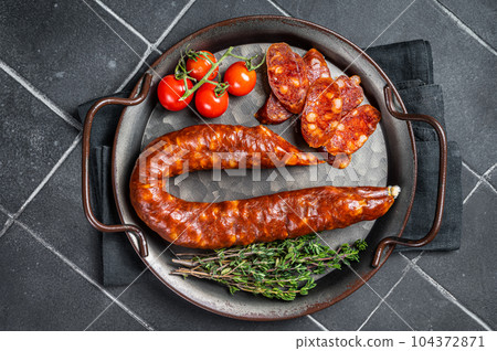 Sliced Chorizo sausage, slices of dry cured pork with herbs and spices. Black background. Top view Sliced Chorizo sausage, slices of dry cured pork with herbs and spices. Black background. Top view 104372871