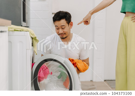 Sad husband being told to wash clothes by his wife. Funny couple. Sad husband being told to wash clothes by his wife. Funny couple. 104373100
