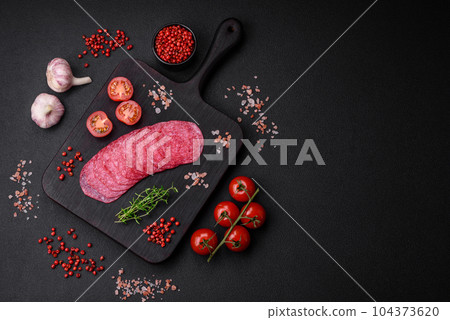 Delicious smoked salami sausage with salt, spices and herbs cut into slices Delicious smoked salami sausage with salt, spices and herbs cut into slices 104373620
