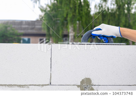 A builder levels a gas block wall with a tool. A builder levels a gas block wall with a tool. 104373748