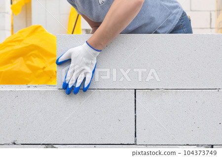 A worker lays a gas block on the wall. 104373749