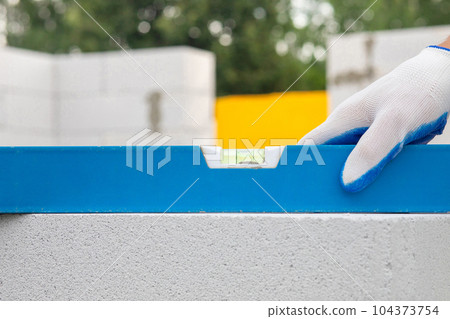 The worker sets the level on the wall of the gas block. The worker sets the level on the wall of the gas block. 104373754