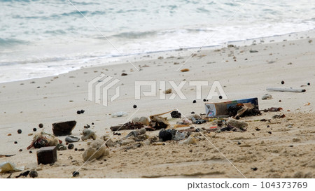 Spilled garbage on the ocean sandy beach. Environmental pollution concept 104373769