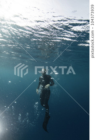 Free diver swimming up on water surface 104373939