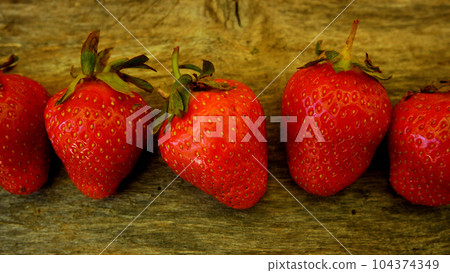 Large red berries of ripe strawberries on a wooden board. Panorama 104374349