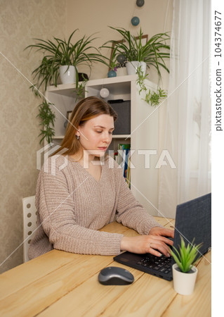 Young female college student sitting at desk at home using laptop. Young female college student sitting at desk at home using laptop. 104374677