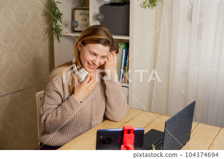 Woman influencer recording video blog on smartphone at home office desk. 104374694