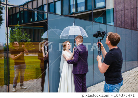 Professional wedding videographer shoots a movie with the newlyweds Professional wedding videographer shoots a movie with the newlyweds 104375471