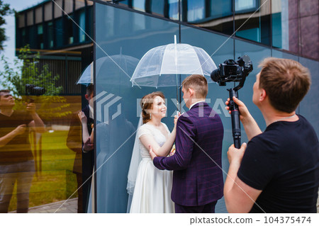 Professional wedding videographer shoots a movie with the newlyweds 104375474