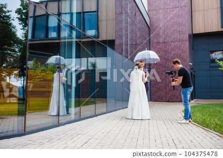 Professional wedding videographer shoots a movie with the newlyweds 104375478