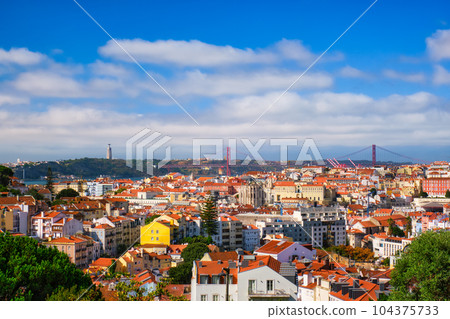 Lisbon famous view from Miradouro dos Barros tourist viewpoint over Alfama old city district, 25th of April Bridge and Christ the King statue. Lisbon, Portugal. 104375733