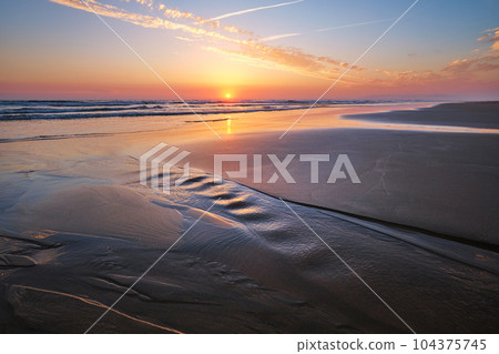 Atlantic ocean sunset with surging waves at Fonte da Telha beach, Costa da Caparica, Portugal 104375745