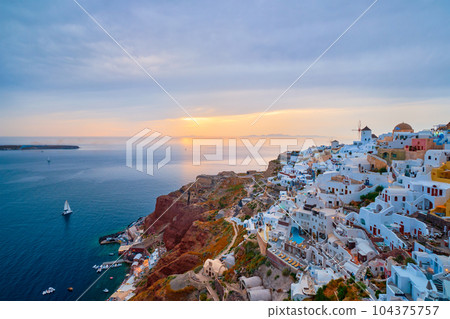 Famous greek iconic selfie spot tourist destination Oia village with traditional white houses and windmills in Santorini island on sunset in twilight, Greece 104375757
