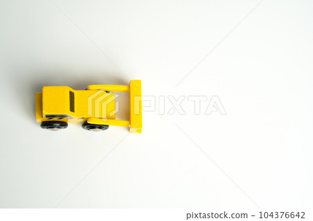 Yellow toy bulldozer, top view copy space. Metaphor to remove something, demolish. Construction works. Clearing and leveling the land. Building destruction. Take down Illegal construction. Industry Yellow toy bulldozer, top view copy space. Metaphor to remove something, demolish. Construction works. Clearing and leveling the land. Building destruction. Take down Illegal construction. Industry 104376642