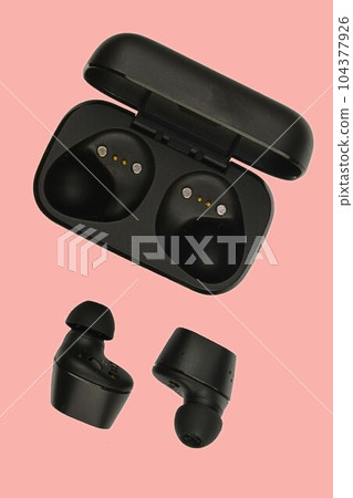 Wireless stereo earbuds. Black wireless earphones and charging case. Earbuds or headphones and charging case with bult-in rechargeable battery for the earbuds isolated on pink background with clipping 104377926