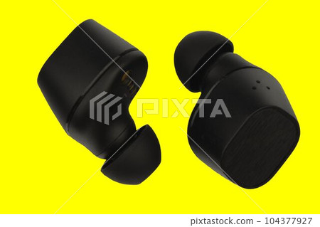 Wireless stereo earbuds. Black wireless earphones. Earbuds or headphones isolated on yellow background with clipping path. Macro horizontal image. Extreme close-up, pastel background. 104377927