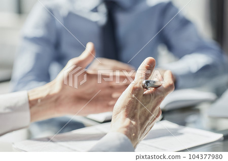 Two business men sit at desk discuss project details Two business men sit at desk discuss project details 104377980