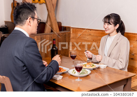 Asian man and woman in suits having dinner in a restaurant Asian man and woman in suits having dinner in a restaurant 104380167