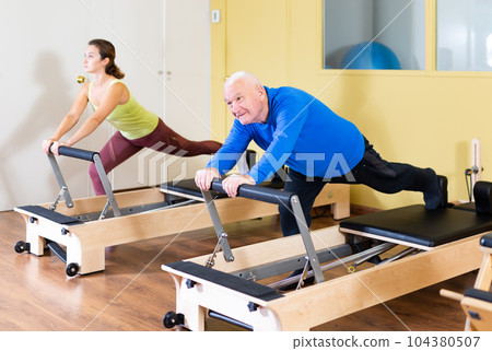 Elderly man press exercises on pilates reformer at studio 104380507
